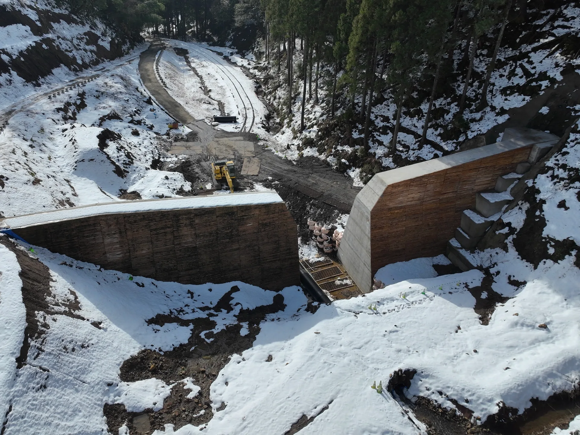積雪した山間部の工事現場を上空から見た様子
